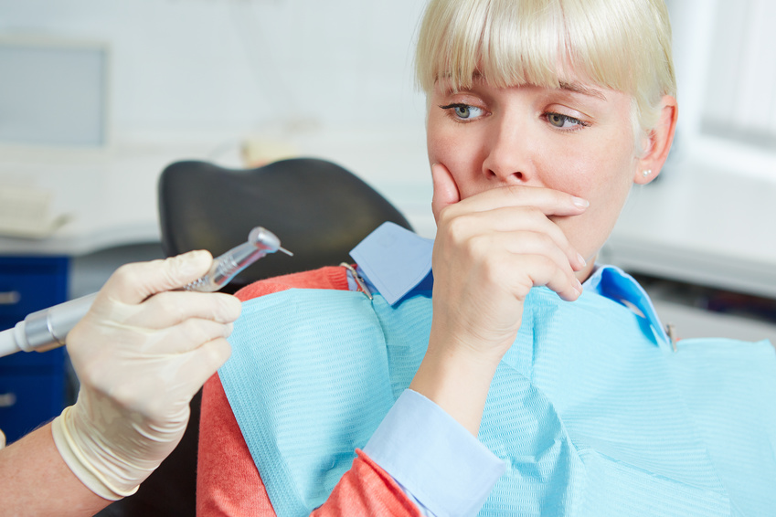 Woman at dental practice refusing dentist treatment with her hand in front of the mouth
